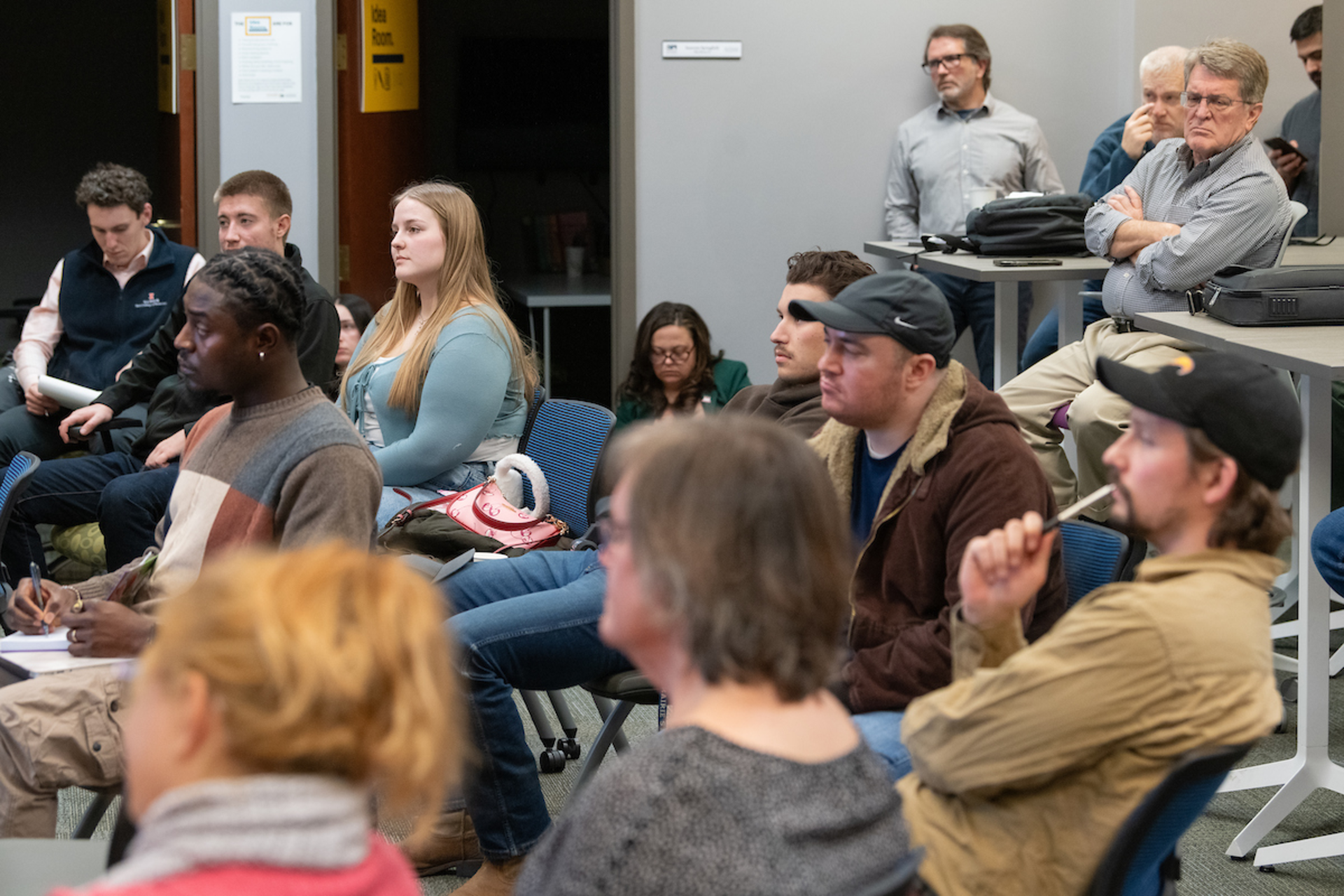 A group of people sit listening to a discussion in a casual, collaborative space.