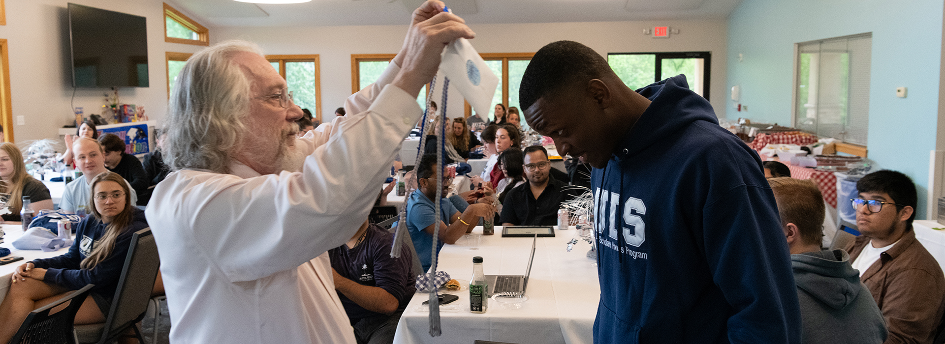 A UIS Professor presents a student with honors cords.